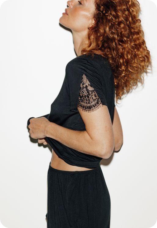 T-shirt noir à manches courtes et détails en dentelle fine.